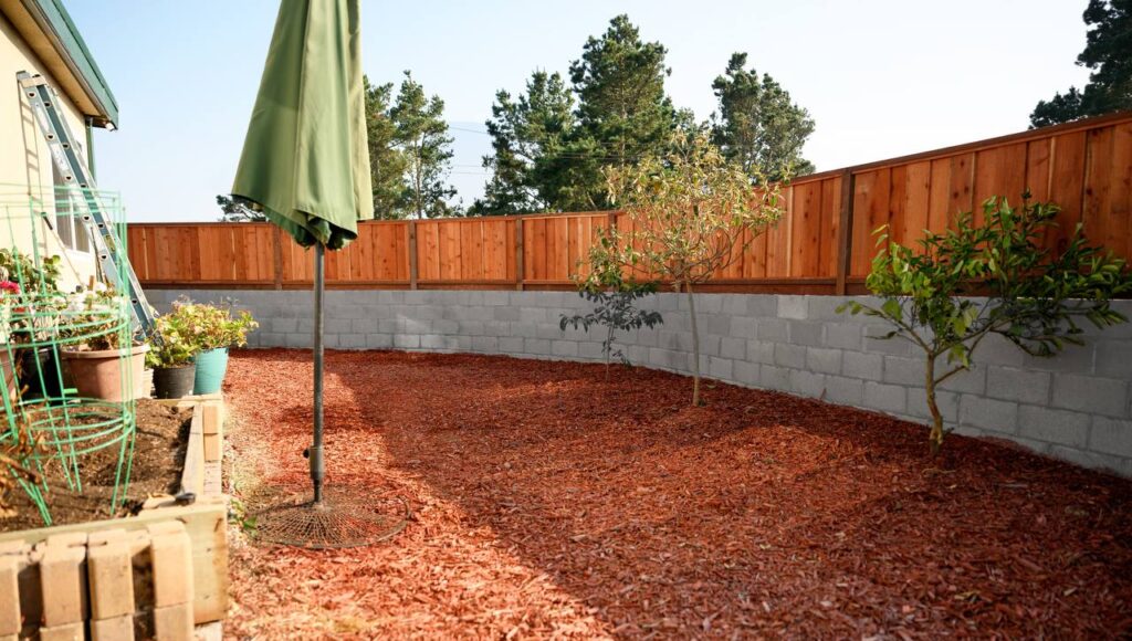 Retaining Walls in Berkeley 32 a fenced backyard with a green umbrella and a tree