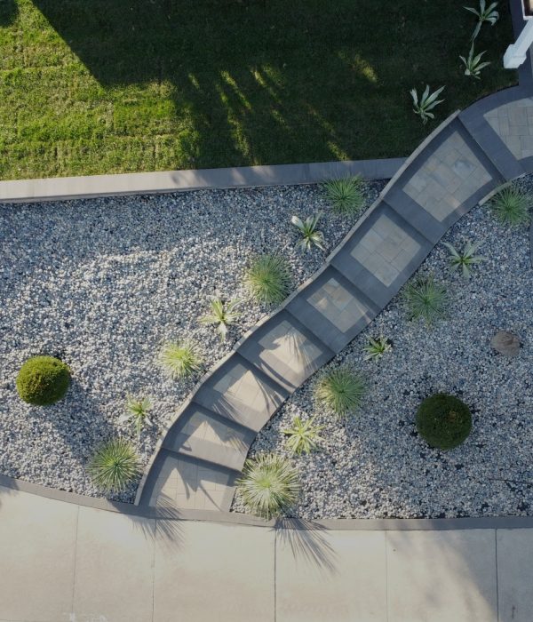 Beautiful landscape design featuring a paver walkway and a stone garden with bushes