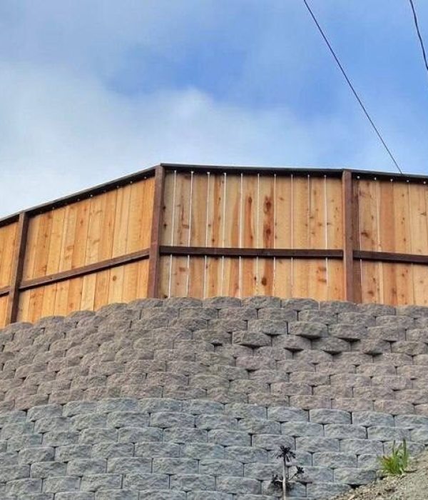 Retaining Wall After Expert fence installation by Geico Builders. View of a strong wooden fence from the exterior of a property